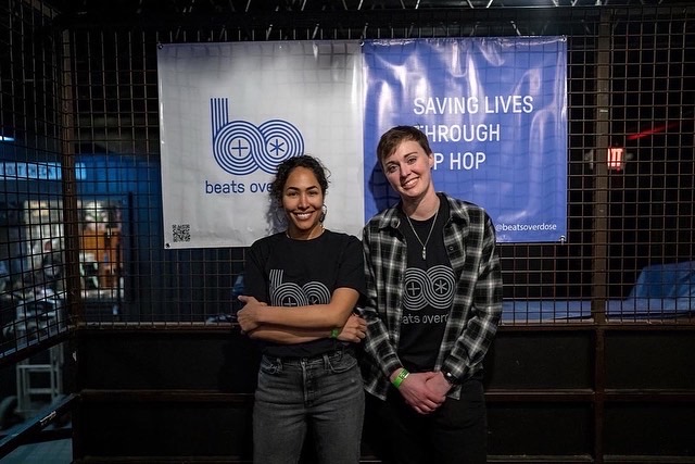 Morgan Godvin and Nikki Jean in front of the Beats Overdose ‘Saving Lives Through Hip Hop’ banner